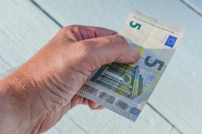 Eine Männerhand reicht einen 5-Euro-Schein